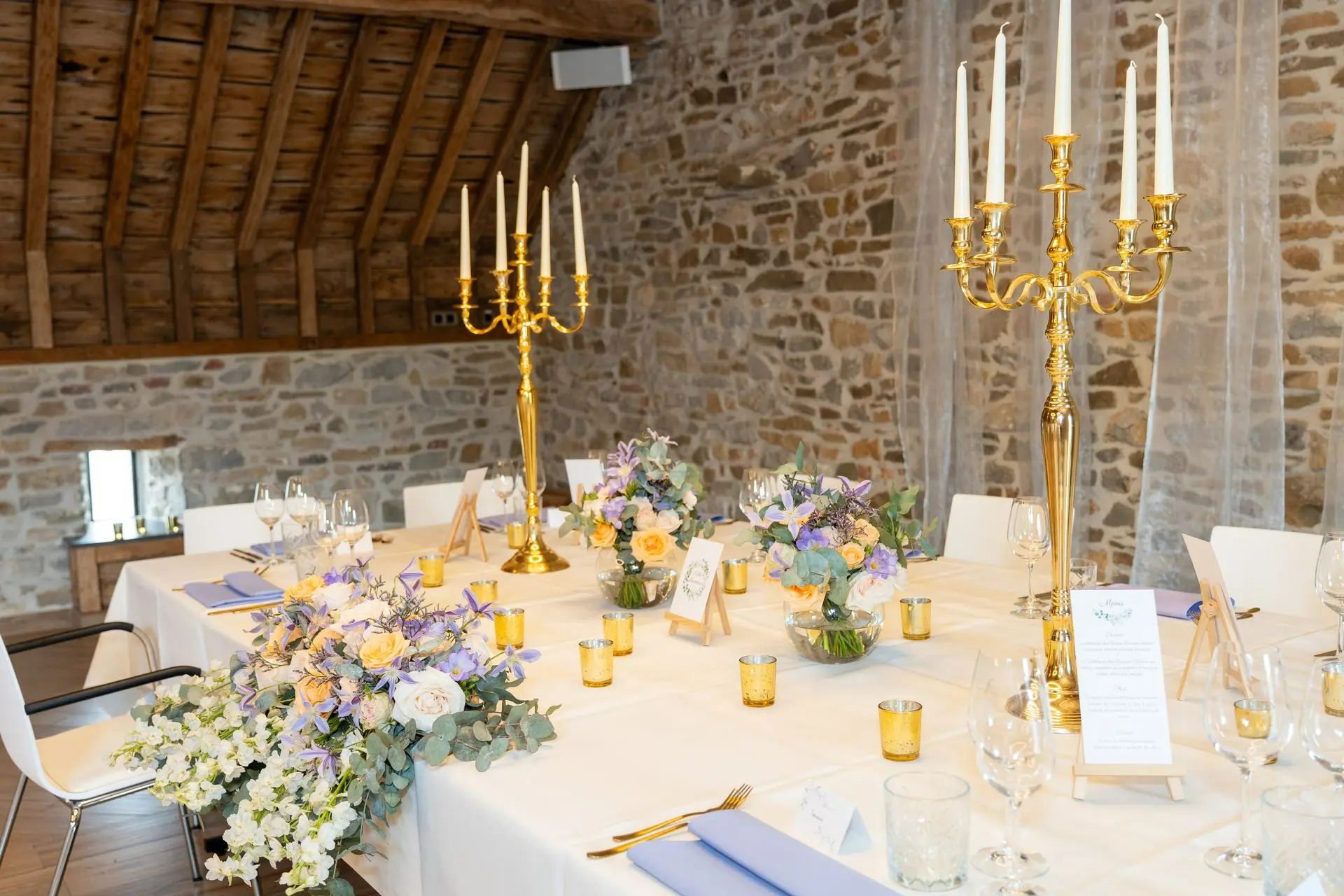 2 chandeliers dorées et fleurs devant les mariées