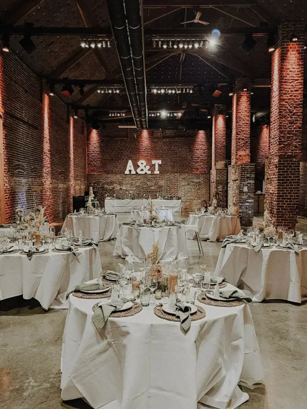 Grange en briques décorée pour un mariage : lettres lumineuses et tables rondes – Ferme de Bertinchamps, mariage de A et T, août 2025