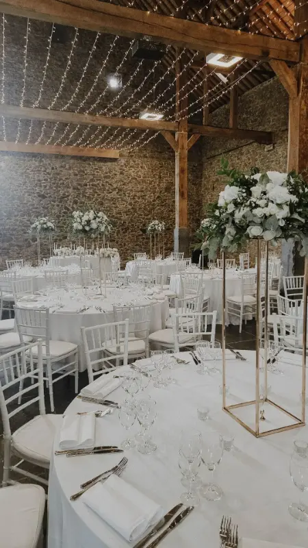 Salle en pierre : chaises Napoléon blanches et compositions florales blanches sur supports dorés – Waerboom, mariage de E et A, juillet 2025