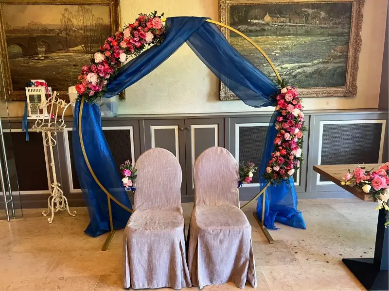 Arche ronde dorée avec voilage bleu et fleurs pour la table des mariés – Château de Huizingen, mariage de V et C, mai 2025