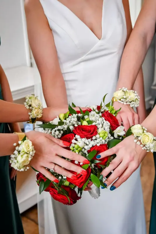 Bouquet de mariée en roses rouges et blanches et bracelets fleuris des demoiselles d'honneur – Château de la Rocq, mariage de L et Q, avril 2025