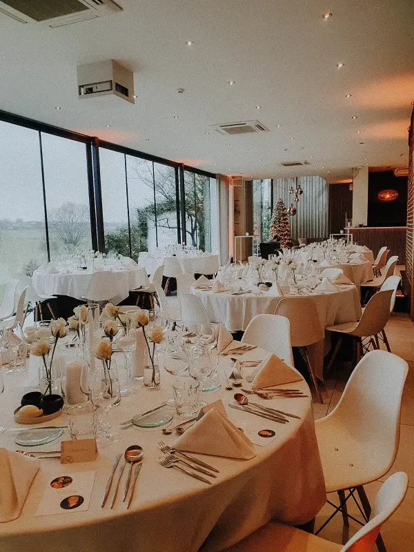 Salle de réception vitrée : tables rondes et centres de table fleuris – Kattebroek, mariage de K et R, janvier 2025