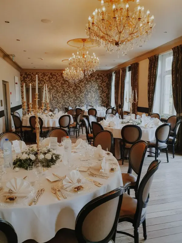 Salle de mariage avec lustres en cristal, chandeliers dorés et tables rondes – Château de Huizingen, mariage de J et A, septembre 2024