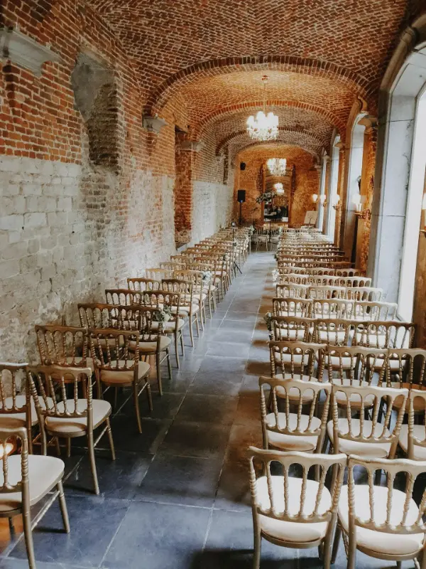 Cérémonie de mariage dans une galerie voûtée en briques avec chaises Napoléon – Abbaye de Nizelles, mariage de M et T, juin 2024