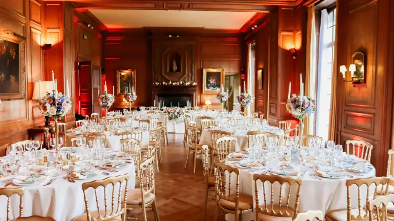 Salon à boiseries avec cheminée : chaises Napoléon dorées et compositions sur chandeliers – Château de La Hulpe, mariage de C et L, mai 2024