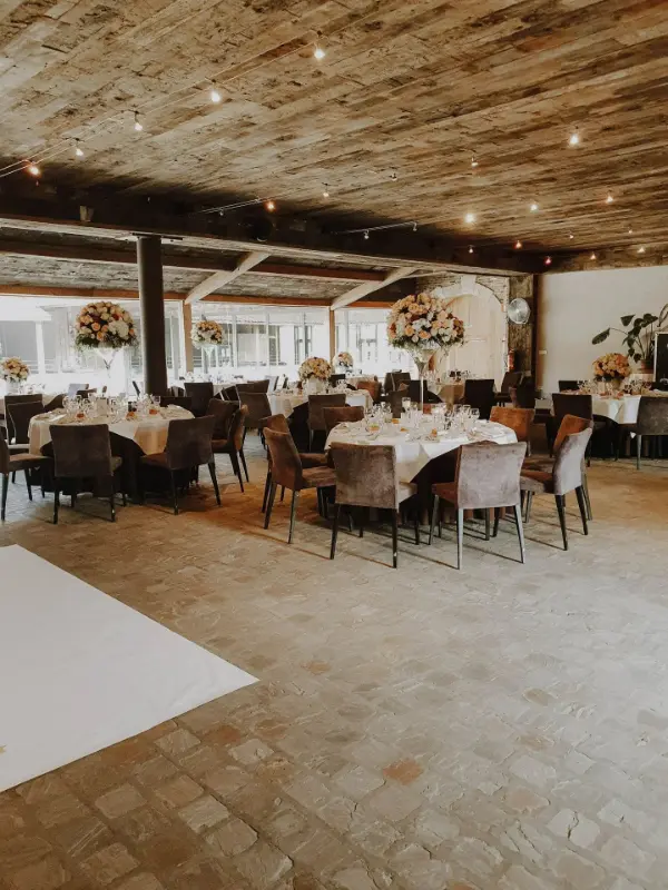 Salle à poutres : tables rondes, chaises en velours et grands centres de table en roses – Waerboom, mariage de A et F, mai 2024