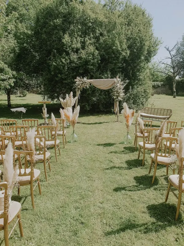 Cérémonie laïque sur pelouse : arche en voilage, herbes de la pampa et chaises Napoléon dorées – Abbaye de Nizelles, mariage de L et A, mai 2024