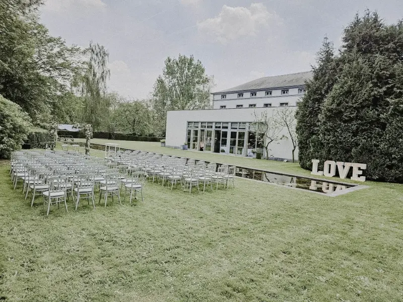 Cérémonie laïque en extérieur : chaises blanches, lettres LOVE lumineuses et plan d'eau – Domaine des Bouleaux, mariage de A et V, mai 2024