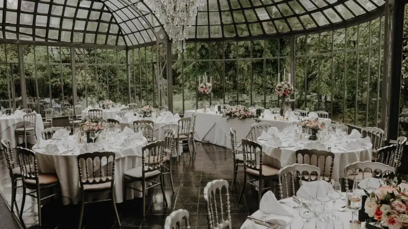 Réception de mariage dans une orangerie : tables rondes et chaises Napoléon – Château de Ruisbroek, mariage de L et R, mai 2024