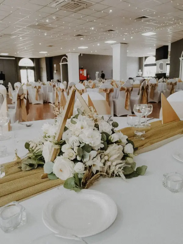 Centre de table en fleurs blanches et housses de chaise à nœuds dorés – Caesar Palace, mariage de L et M, juillet 2023
