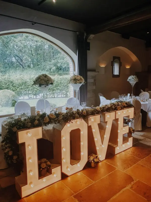 Lettres LOVE lumineuses avec guirlande florale et compositions sur grands vases – Waerboom, mariage de A et M, juillet 2023