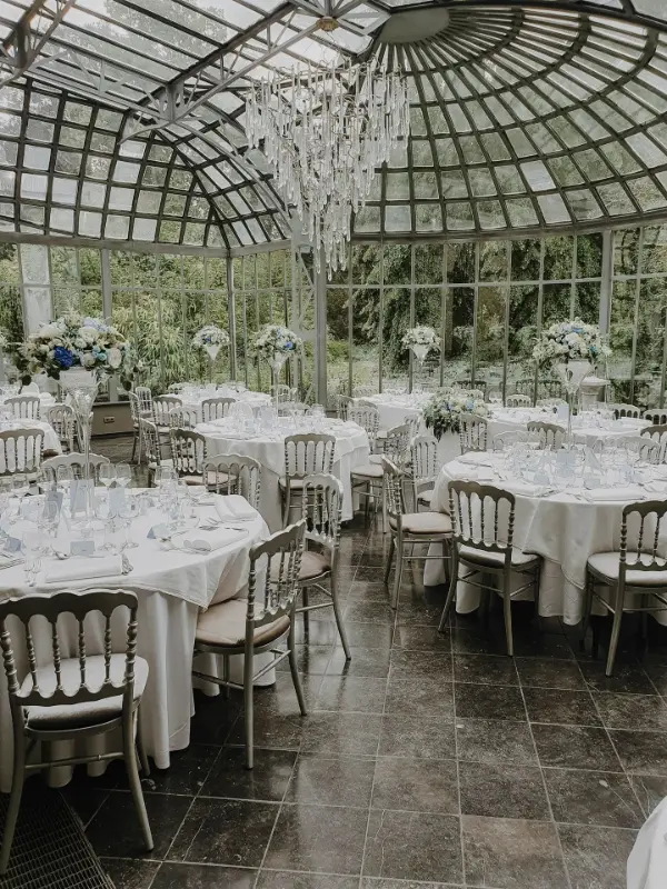 Orangerie : chaises Napoléon et hautes compositions en fleurs blanches et bleues – Château de Ruisbroek, mariage de A et M, juillet 2023