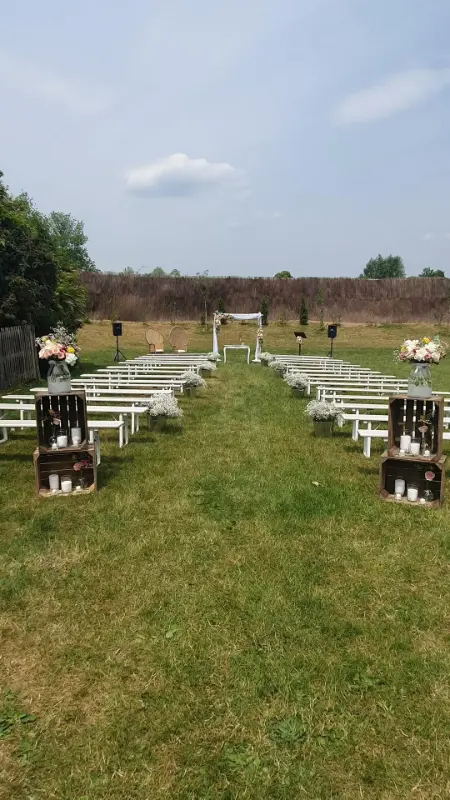 Cérémonie laïque dans un jardin : bancs blancs, caisses en bois et bougies – Ferme de Bertinchamps, mariage de V et A, juin 2023