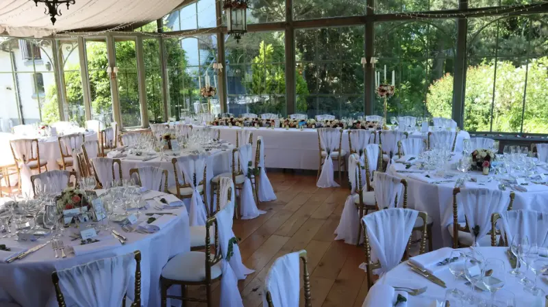 Véranda : housses de chaise blanches et tables rondes – Abbaye de Nizelles, mariage de P et M, juin 2023