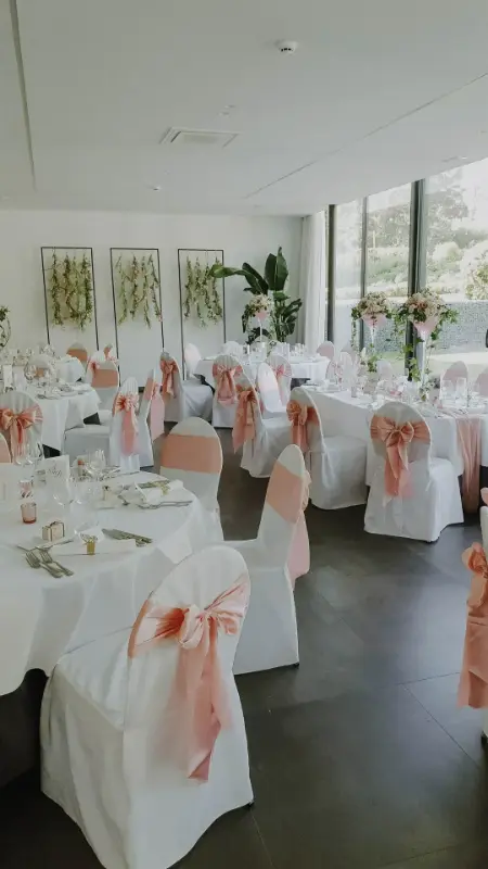 Housses de chaise blanches avec nœuds roses et tables rondes – Salons de Romree, mariage de N et M, mai 2023