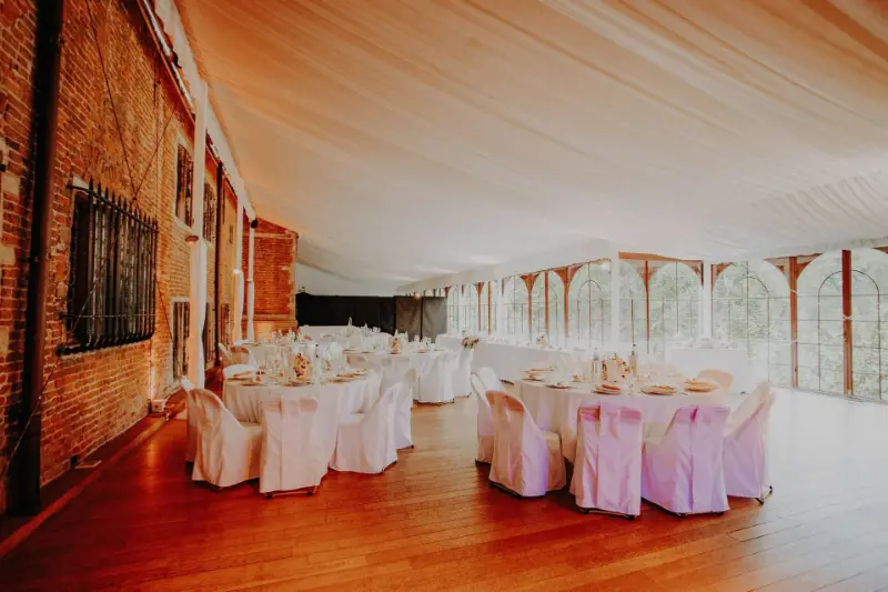 Salle drapée : housses de chaise blanches et nœuds roses – Château de Grand-Bigard, mariage de A et G, septembre 2022