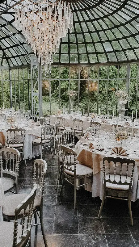 Verrière : chaises Napoléon argentées et tables rondes – Château de Ruisbroek, mariage de M et A, septembre 2022