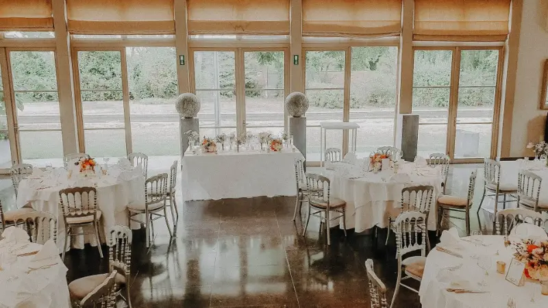 Salle avec véranda : tables rondes dressées pour un mariage – Domaine des Bouleaux, mariage de AS et R, août 2022