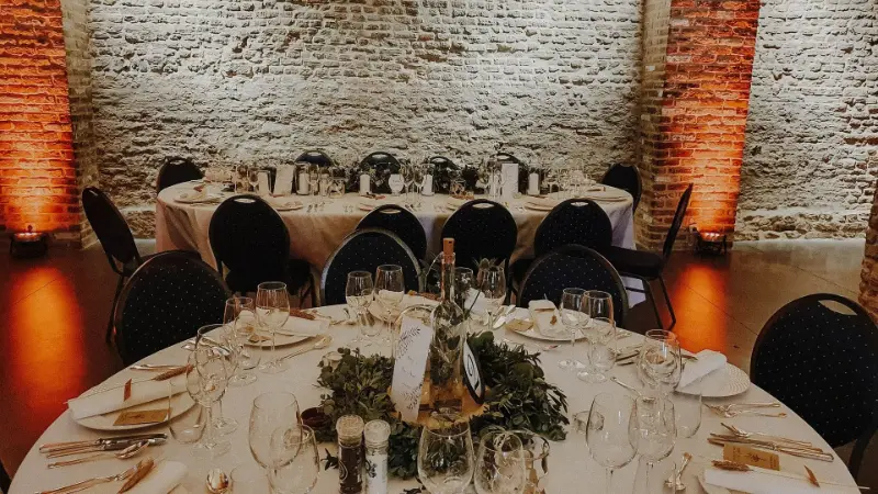 Salle en pierre et briques : chaises noires et centre de table en verdure – Clos Saint-Michel Upigny, mariage de A et A, juillet 2022