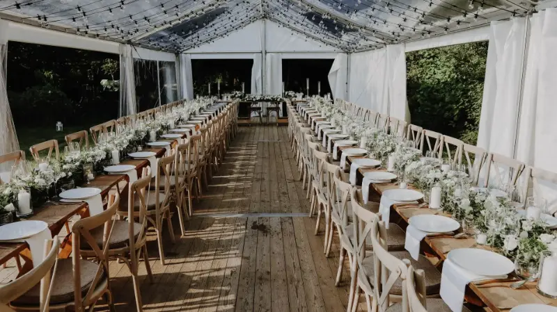 Longues tables sous tente avec chaises en bois – mariage de R et J, septembre 2021
