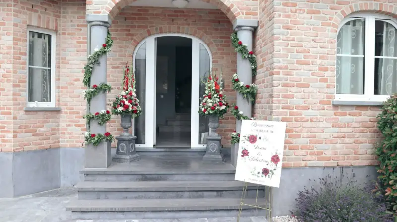 Entrée décorée de guirlandes et fleurs rouges avec panneau de bienvenue – mariage de L et L, juillet 2021