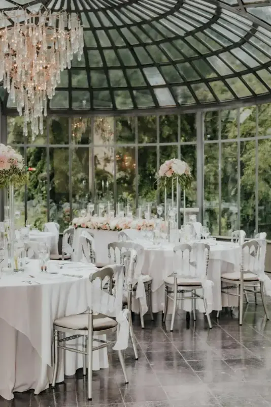 Verrière : hautes compositions de roses pâles et chaises Napoléon blanches – Château de Ruisbroek, mariage de M et L, juillet 2021