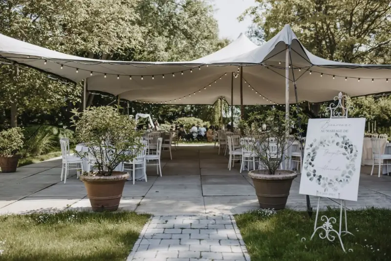 Réception en jardin sous tente avec oliviers en pot et panneau de bienvenue – La Maison Basse, mariage de G et A, juin 2021