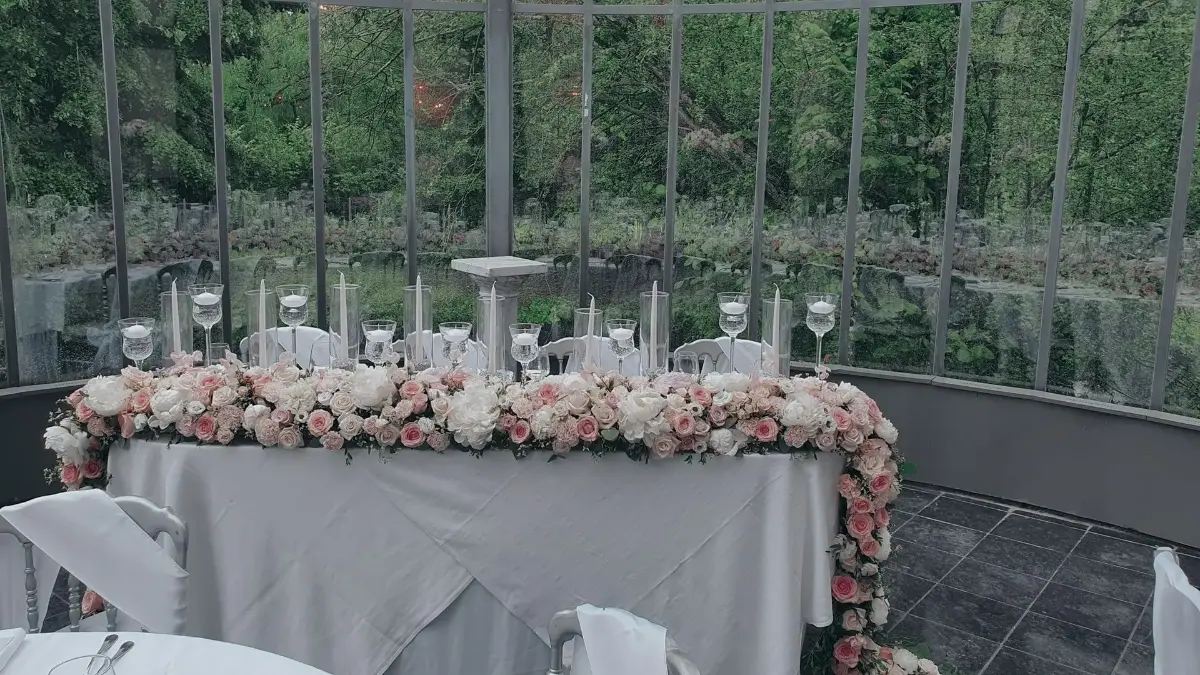 Table d'honneur avec chemin floral rose devant des baies vitrées – Château de Ruisbroek, mariage de Meryam et Lorenzo